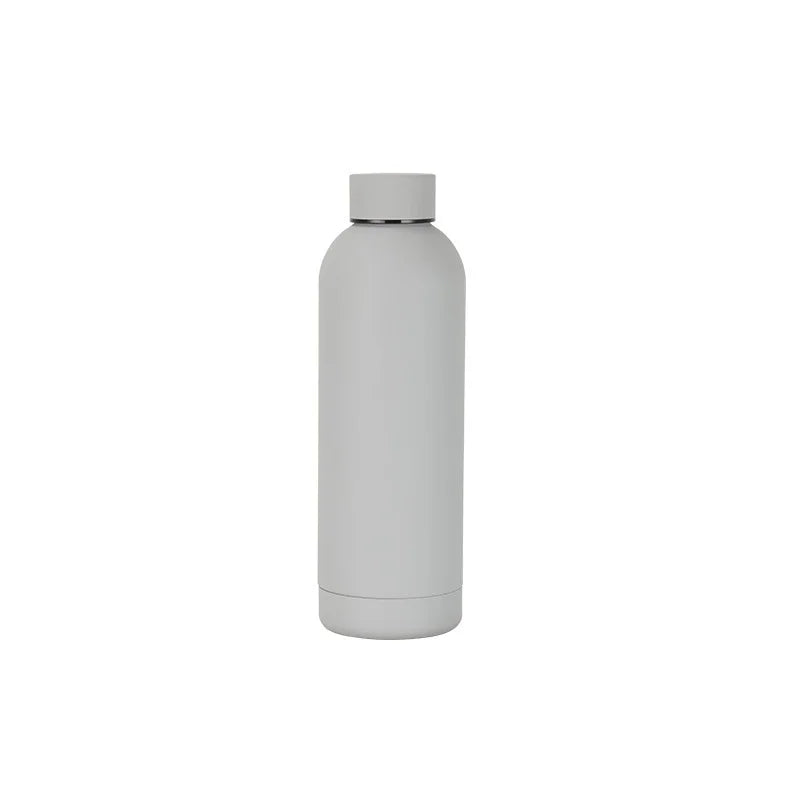 Stainless steel thermos bottle placed on a hiking trail, designed for outdoor sports, trekking, and travel.